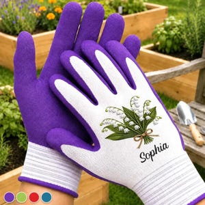 Può includere: Un paio di guanti da giardinaggio con il dorso di un vivace colore viola e il palmo bianco. Il palmo bianco presenta un dettagliato bouquet ricamato di mughetti legato con un nastro marrone e il nome Sophia stampato in corsivo nero.