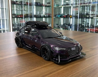 May include: A dark purple Audi RS6 Avant scale model car featuring a black roof cargo box, wide fender flares, black multi-spoke wheels, a front splitter with support rods, and a black honeycomb grille with the Audi logo and quattro emblem.