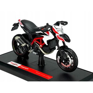 Może przedstawiać: Szczegółowy model motocykla Ducati Hypermotard SP. Miniaturowy motocykl ma czarne siedzenie, czerwoną ramę oraz białe i czerwone akcenty. Model jest zamontowany na czarnej podstawie z logo Ducati i napisem "Hypermotard SP".