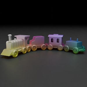 以下が含まれることがあります： カラフルなおもちゃの電車。機関車と3つの客車で構成されています。機関車は黄色、2両目はピンク、3両目は紫、最後は緑です。電車には車輪があり、子供向けに設計されています。