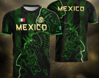 May include: A black and green short-sleeve t-shirt featuring the word MEXICO in gold lettering, a small Mexican flag, and a graphic of an eagle perched on a cactus. The design includes a repeating pattern and a large eagle illustration on the back.