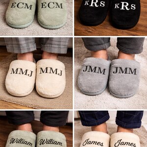May include: A collection of personalized slippers in various colors, including black, gray, and cream. Each pair features embroidered initials or names in a contrasting color. The slippers are soft and cozy, perfect for lounging at home.