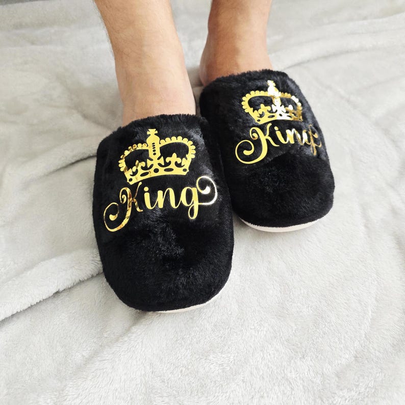 King crown slippers worn on feet, featuring metallic gold crown and script lettering — luxurious custom men's slippers.
