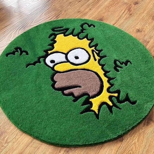 May include: A round green rug featuring a yellow cartoon character with a surprised expression. The character's face is in the center, with a brown mouth and large white eyes. The rug has a green border and is placed on a wooden floor.