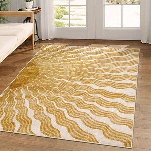 May include: A rectangular area rug with a sun design. The rug features a golden yellow sun on the left side, with wavy lines radiating across a cream-colored background. The rug is placed on a hardwood floor.