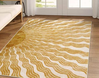 May include: A rectangular rug with a sun design. The rug features a golden yellow sun on the left, with wavy lines radiating across a cream background. The rug is placed on a wooden floor.