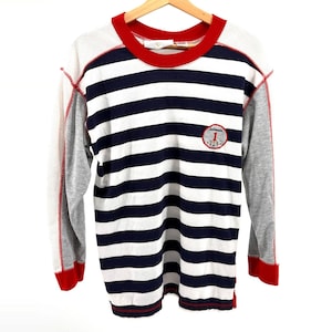 May include: A long-sleeved shirt with a red collar and cuffs, featuring alternating white and navy blue horizontal stripes. The sleeves are gray with red stitching. A small patch with the number "1" is on the chest.