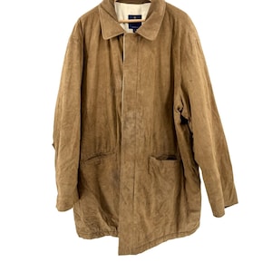 May include: A tan suede jacket featuring a pointed collar, long sleeves, and two front pockets. The jacket has a button-front closure hidden by a placket and a light-colored interior lining. A dark blue brand label is visible at the inner neckline.