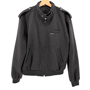 May include: A white ceramic mug with a black handle and the text "But First, Coffee" in a bold, black font. The mug is set against a blurred background, suggesting a cozy setting.