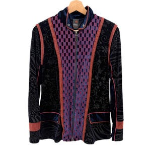 May include: A long-sleeve zip-up jacket featuring a central panel with a purple and blue checkerboard pattern. The jacket is made of dark blue velvet with black floral and animal print accents, finished with rust-colored piping and trim details.
