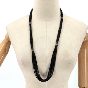 Collar llamativo vintage negro de múltiples hebras con cuentas de vidrio y detalles en tono plateado.