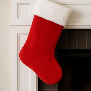 May include: A red Christmas stocking with a white faux fur cuff hangs from a white mantelpiece. The stocking is made of a felt-like material and has a red ribbon loop for hanging. The background includes a fireplace.