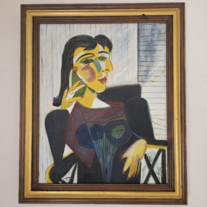 May include: A white ceramic mug with a black handle and the text "But First, Coffee" in a bold, black font. The mug is set against a blurred background, suggesting a cozy setting.