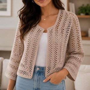 Peut inclure: Un gilet beige ouvert sur le devant avec un motif en crochet complexe, une encolure carrée et des manches trois-quarts. Le vêtement est porté sur un haut blanc uni et un jean bleu clair, mettant en valeur un design en maille ajourée détaillé.