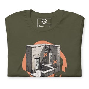 Può includere: T-shirt verde oliva con un'illustrazione architettonica surrealista. Il design presenta una struttura in pietra con una scala, una porta aperta e croci arancioni. La maglietta ha un'etichetta con la scritta "XS Nicaragua".