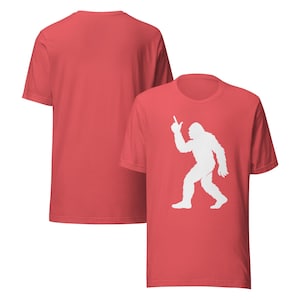May include: Two red t-shirts. One shirt features a white silhouette of Bigfoot pointing upwards. The other shirt is plain red. Both shirts have short sleeves and a crew neck.