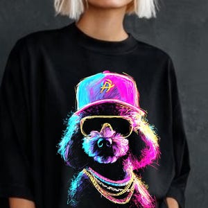 Puede incluir: Camiseta negra con un gráfico colorido de un caniche con gorra de béisbol, gafas de sol y una cadena de oro. La imagen del caniche está representada en colores neón vibrantes. La gorra tiene la letra "A".