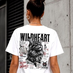 May include: A white t-shirt featuring a black and white graphic print on the back. The design includes the text WILDHEART, a detailed illustration of a Maine Coon cat wearing a collar, and various technical-style text elements and barcodes.