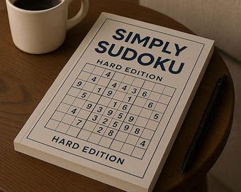 May include: A white mug filled with coffee sits next to a "Simply Sudoku Hard Edition" book and a black pen on a wooden table. The book features a grid with numbers, and the title is in blue.