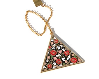 May include: Gold triangle-shaped pendant with a black enamel background and a floral design in red, white, and pink. The pendant is attached to a gold chain with a gold clasp.