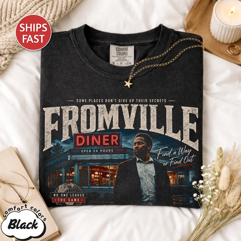 Peut inclure: T-shirt noir Comfort Colors avec un motif graphique de la s&eacute;rie Fromville. Le motif comprend le texte "Fromville Diner" avec une image d'un restaurant et la phrase "Find a Way or Find Out."