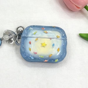 Puede incluir: Una funda azul de forma cuadrada con una cubierta transparente. La funda presenta un diseño caprichoso de peces de colores nadando alrededor de una estrella amarilla. Un cierre de metal plateado y un dije decorativo están adjuntos.