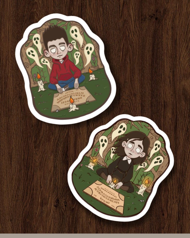 May include: Two die-cut stickers with illustrations of people using Ouija boards. One sticker shows a person in a red hoodie, the other in a black dress. Both are surrounded by ghosts and candles. The Ouija boards have the alphabet, numbers, and the word "Ouija" printed on them.