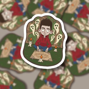 May include: A sticker with a cartoon illustration of a person in a red hoodie sitting cross-legged before a Ouija board. White ghost figures and lit candles surround the person. The background is a green forest scene.