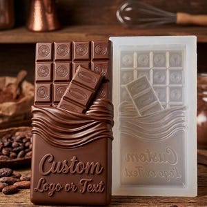 Può includere: Uno stampo rettangolare per tavolette di cioccolato in silicone traslucido accanto a una tavoletta di cioccolato finita. La tavoletta presenta una griglia di quadrati con centri circolari, un pezzo rotto sopra e il testo Custom Logo or Text.