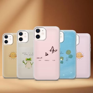 Pode incluir: Uma coleção de capas de telefone com vários designs. Uma capa apresenta um gráfico de sol e o texto "LIFE IS TOUGH BUT SO ARE YOU." Outra tem uma ilustração de sapo. Uma terceira capa tem um gráfico de borboleta e as palavras "GIVE YOURSELF TIME."
