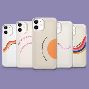 Può includere: Una collezione di cinque custodie per telefoni con vari disegni e testo. Le custodie sono principalmente beige e bianche, con accenti colorati come un arcobaleno e un cerchio arancione. Il testo include frasi come "live in the moment" e "The sun will rise again tomorrow."