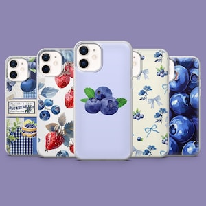 Puede incluir: Una colección de fundas para teléfonos con varios diseños. Una funda presenta una ilustración de acuarela de arándanos con hojas verdes. Otras fundas muestran fresas, arándanos y patrones florales. Las fundas están sobre un fondo morado.