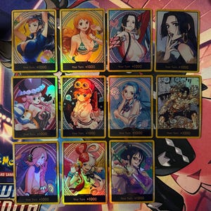 May include: Twelve trading cards with anime-style character illustrations, each with a gold border and the text "Your Turn +1000". The cards are displayed on a patterned surface with a variety of colours.