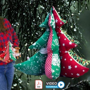以下が含まれることがあります： 雪の結晶と星の模様が入った赤と緑の生地で作られた手作りのクリスマスツリーのオーナメント。オーナメントはクリスマスツリーの形をしています。画像には、同様のオーナメントを持っている人も写っています。