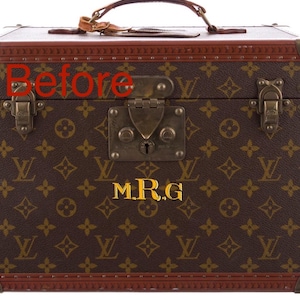 May include: A brown and tan monogrammed travel case with a leather handle and brass hardware. The case features a repeating logo pattern and the gold initials "M.R.G". The case is rectangular with brown leather trim.