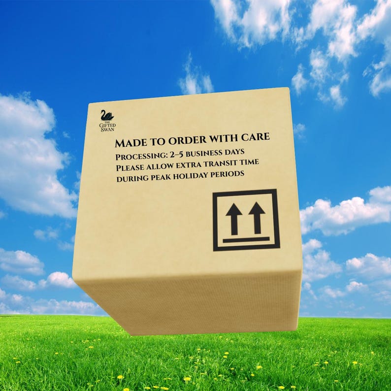May include: A tan cardboard shipping box featuring a black swan logo and the text MADE TO ORDER WITH CARE, PROCESSING: 2-5 BUSINESS DAYS, PLEASE ALLOW EXTRA TRANSIT TIME DURING PEAK HOLIDAY PERIODS, and a black upward-pointing arrow symbol.