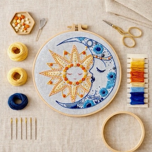 Peut inclure: Un cercle à broder avec un motif de soleil et de lune en fil jaune, orange et bleu. L'image comprend des bobines de fil jaune et bleu, des aiguilles, des ciseaux et d'autres fournitures d'artisanat, suggérant un kit de bricolage.