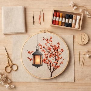 Peut inclure: Un kit de broderie comprenant un tambour en bois rond avec un motif brodé de lanterne suspendue et d'un arbre aux baies orange. Inclut un tissu beige rectangulaire, des ciseaux dorés, des aiguilles et une boîte en bois avec huit bobines.