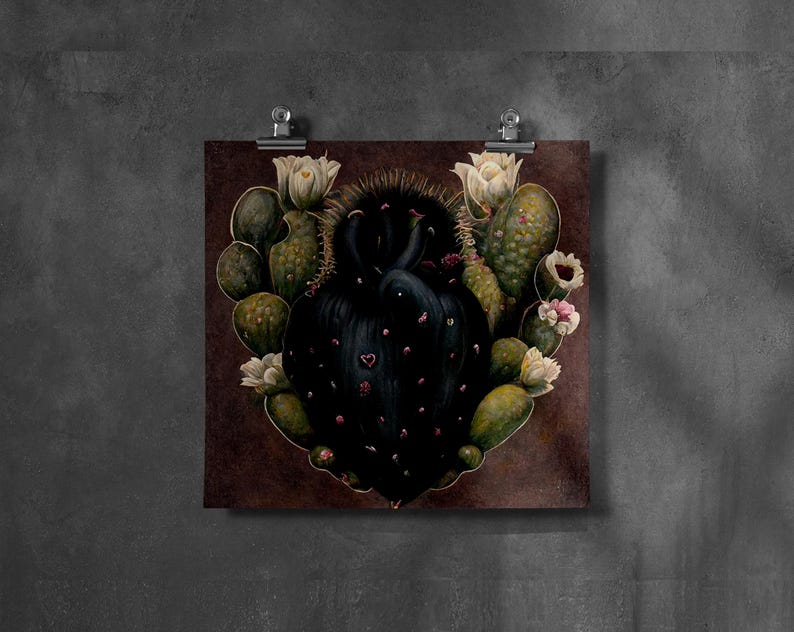 May include: A square print featuring a heart-shaped cactus with a dark, textured center and green, oval-shaped segments. The cactus is adorned with white and pink flowers. The print is attached to a dark brown background with silver clips.