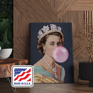 Op de afbeelding: Een canvas print met een portret van een vrouw met een kroon en sieraden, die een grote roze kauwgomballenblaas blaast. De afbeelding heeft een donkere achtergrond. Een "MADE IN U.S.A." sticker is linksonder zichtbaar.