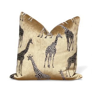 Könnte beinhalten: Dekoratives Kissen mit goldenem Hintergrund und einem sich wiederholenden Muster aus schwarz-weißen Giraffen. Das Kissen hat ein weiches, strukturiertes Aussehen und eine quadratische Form, ideal für einen Hauch von Safari-Stil.