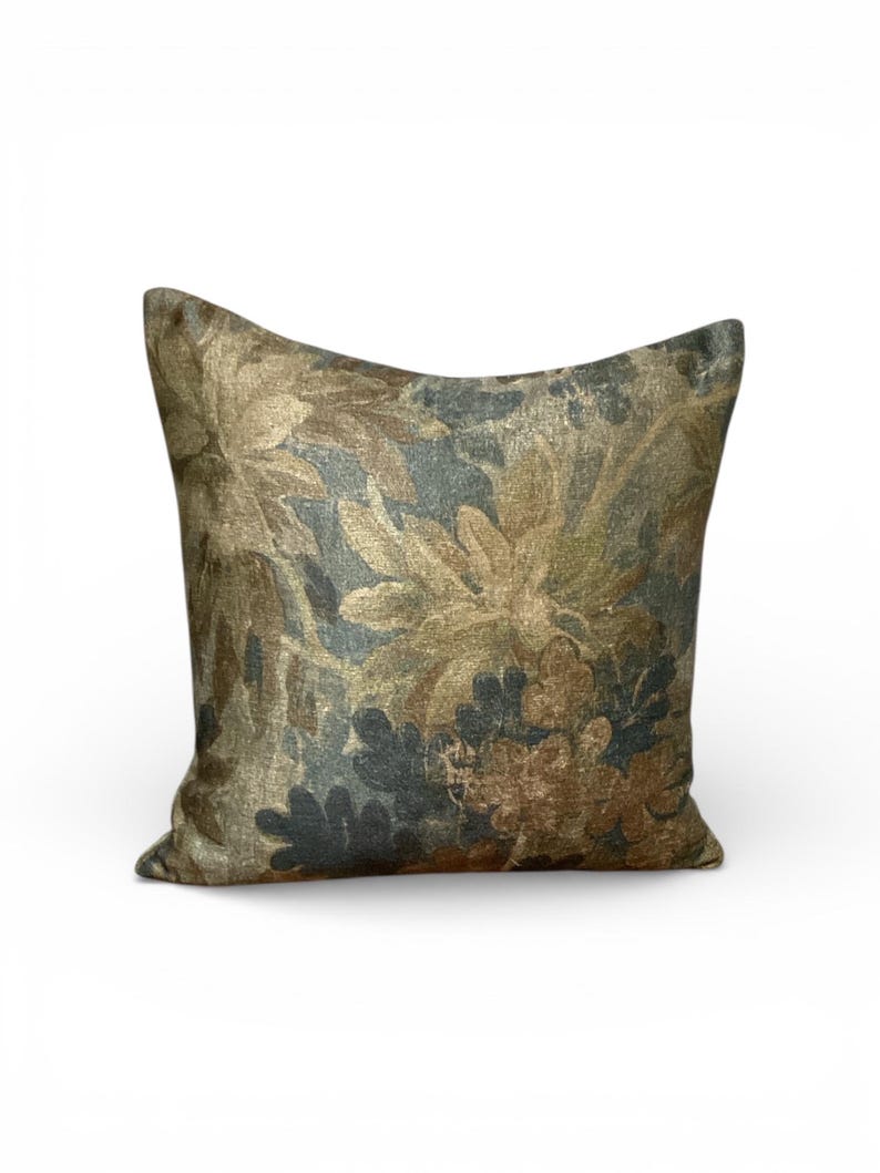K&ouml;nnte beinhalten: Quadratisches Zierkissen mit floralem Muster in Gold-, Braun- und Blaugr&uuml;nt&ouml;nen. Der Stoff wirkt strukturiert, mit einem Design aus stilisierten Bl&auml;ttern und Blumen. F&uuml;r Sofa oder Bett geeignet.