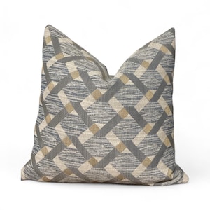 May include: Square cushion with a geometric pattern. The cushion has a woven design with intersecting lines in shades of grey, beige, and light blue. The pattern creates a textured appearance, suitable for home decor.