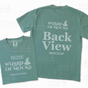 Op de afbeelding: Twee saliegroene t-shirts, één opgevouwen en één uitgevouwen, met witte tekst. Het opgevouwen shirt toont "Real Product Photography" en "Wizard of Mocks Mockup Shop". Het uitgevouwen shirt toont "Back View Mockup" en het Wizard of Mocks logo.