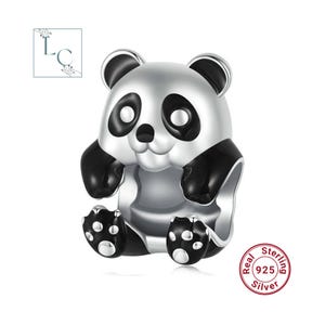 May include: A silver charm bead shaped like a panda with black enamel detailing on the ears, eyes, limbs, and feet. The panda has a polished metallic finish and a central opening for a bracelet. A circular stamp reads Real Sterling 925 Silver.