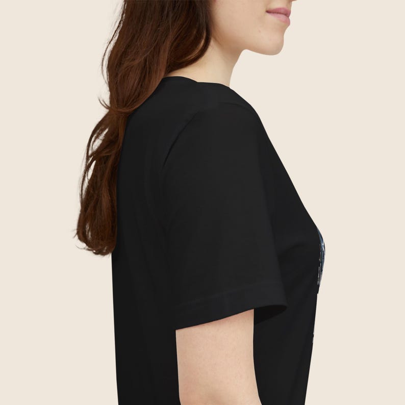 Pu&ograve; includere: T-shirt nero a maniche corte. La maglietta ha uno scollo tondo ed &egrave; realizzata in un materiale morbido. L'immagine mostra la vista laterale della maglietta su una persona.
