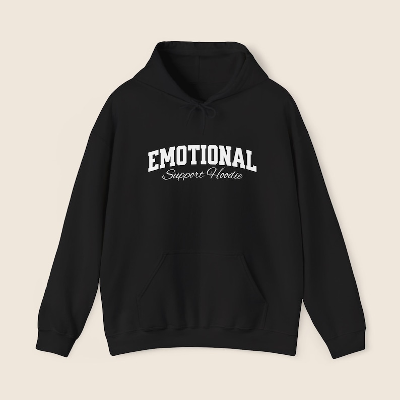 May include: Black hoodie with a front pocket and drawstring hood. The white text on the front reads "EMOTIONAL Support Hoodie". The hoodie is made of a soft material.