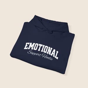 May include: Navy blue hoodie with the words "EMOTIONAL" in bold white letters arched across the top, and "Support Hoodie" in a script font below. The hoodie has a drawstring hood.