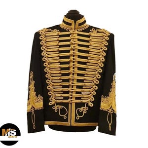 May include: Black military-style jacket with gold-colored decorative trim. The jacket features a high collar and ornate gold rope detailing across the chest and sleeves. The sleeves have gold embroidery. The jacket is displayed on a black mannequin head.
