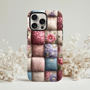 Puede incluir: Una funda de teléfono con un diseño de patchwork. La funda presenta un patrón de cuadrados en varios colores, incluyendo beige, rosa, azul y burdeos. Cada cuadrado tiene un diseño floral o texturizado diferente. La funda tiene un borde negro y recortes para la cámara.